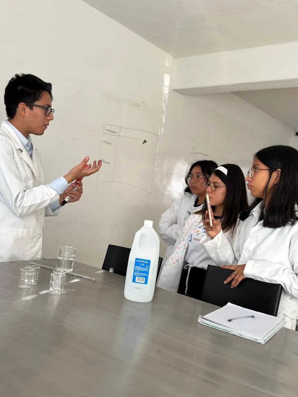 Docente explicando de cerca a un grupo pequeño de alumnos en el laboratorio