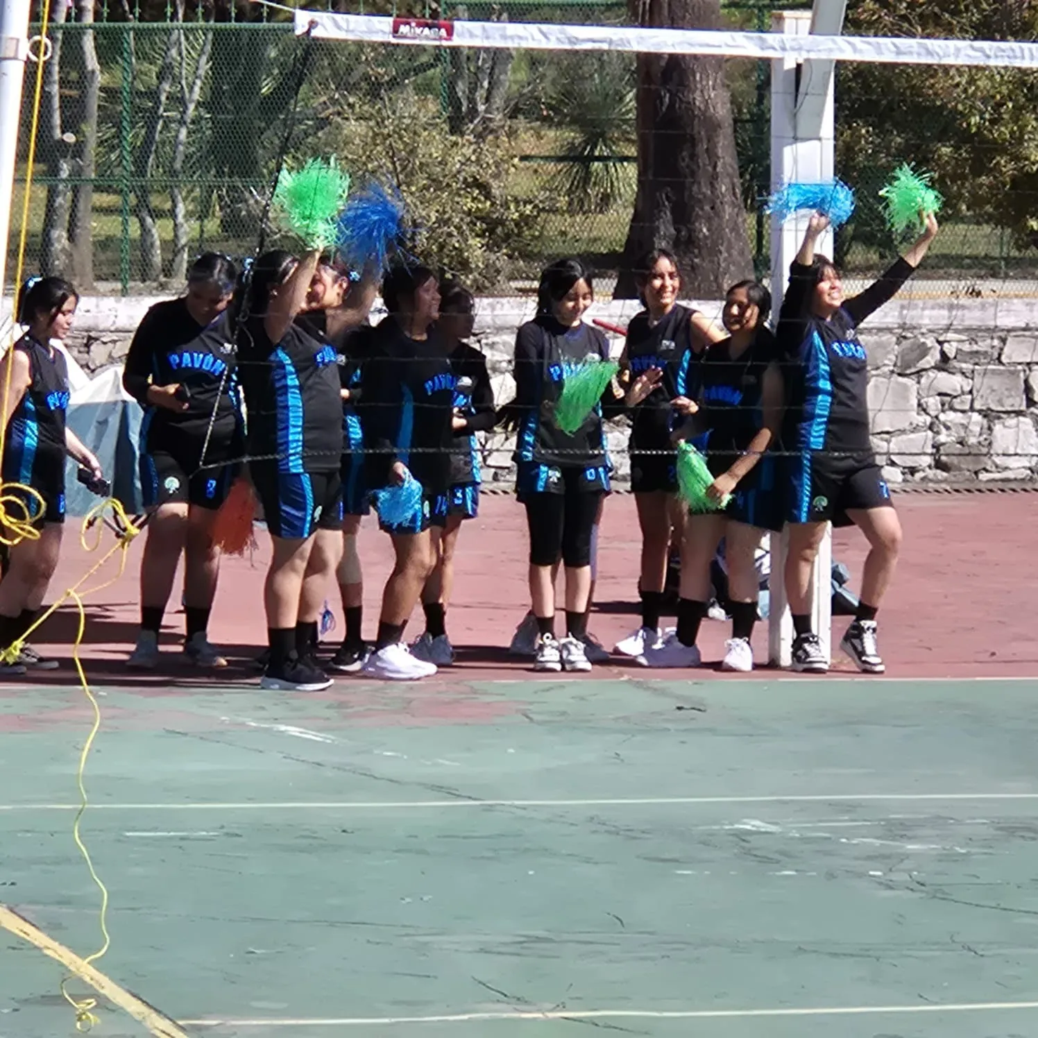 La porra del equipo con pompones en el torneo de voleibol