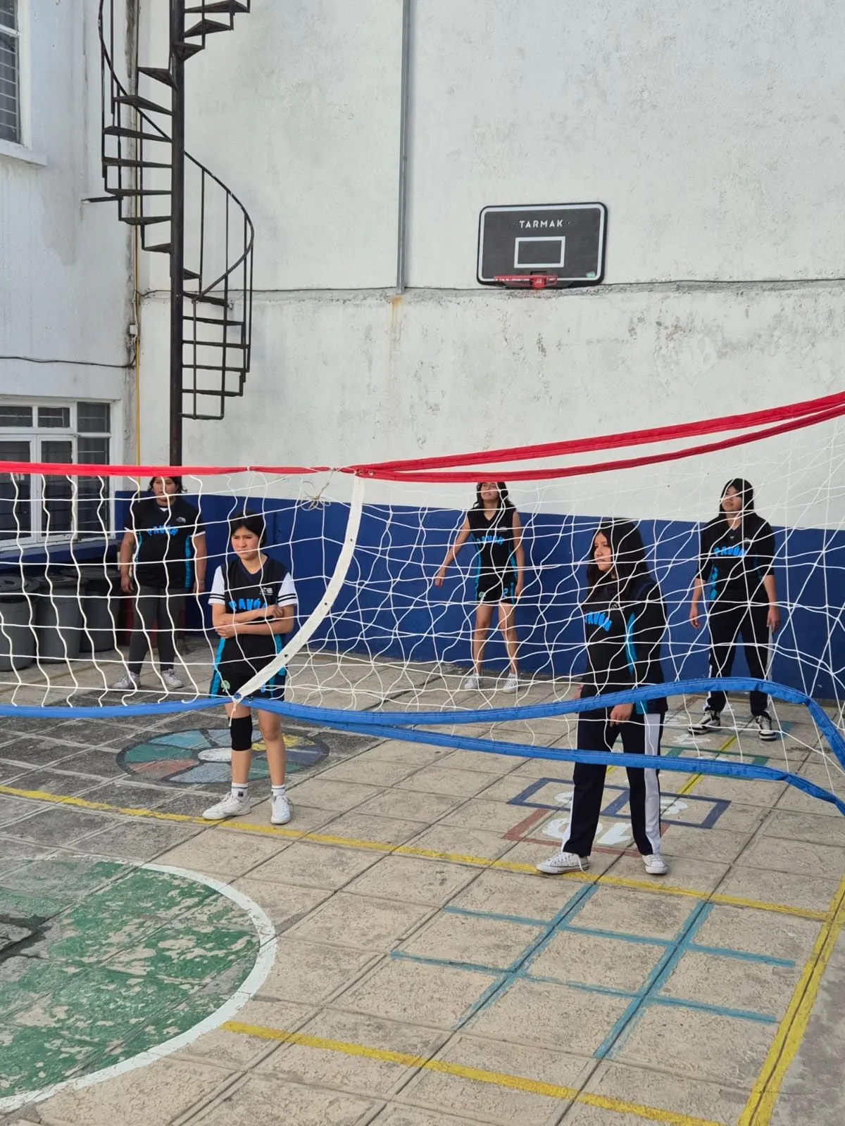 Alumnas jugando voleibol en el patio de la escuela